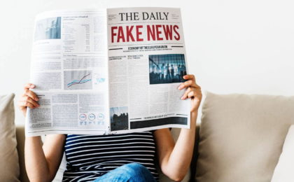 woman holding newspaper with fake news headline